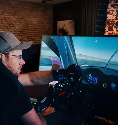 Fahrer im ZEEEM RACR R CORE in einem heimischen Gaming-Setup während einer Rennsimulation.